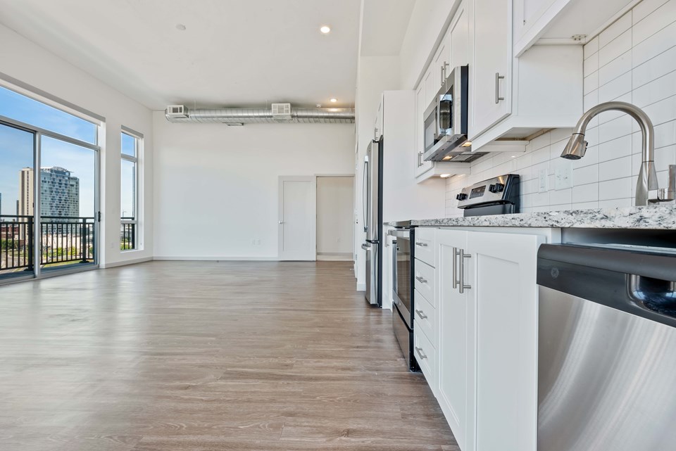 Apartment amenities include modern finishes, granite countertops, tile backsplashes, stainless steel appliances and exposed concrete ceilings. (Photo credit: Kaltenbach Photography)